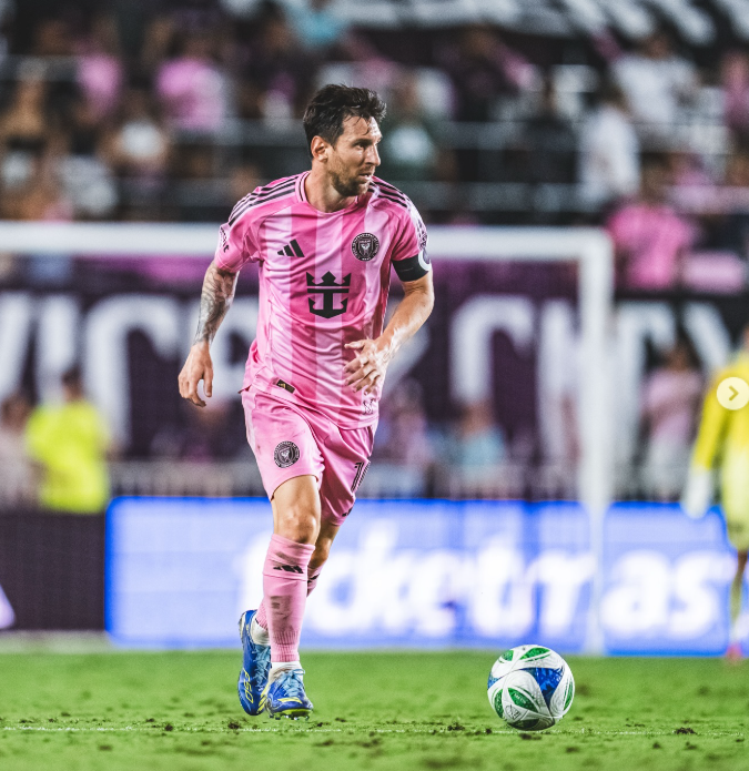 Lionel Messi wearing a pink Inter Miami jersey dribbling the ball on the field during a professional soccer match.