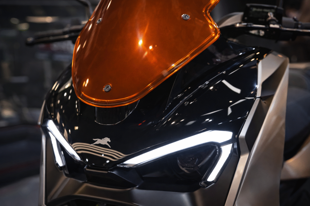 Close-up of TVS M1-S electric scooter front showcasing amber windscreen and LED headlamps