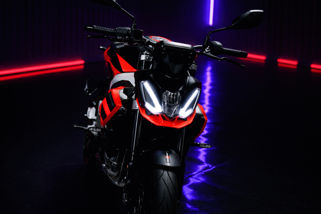Aprilia Tuono 457 front view with sharp LED headlight design in neon-lit studio setting